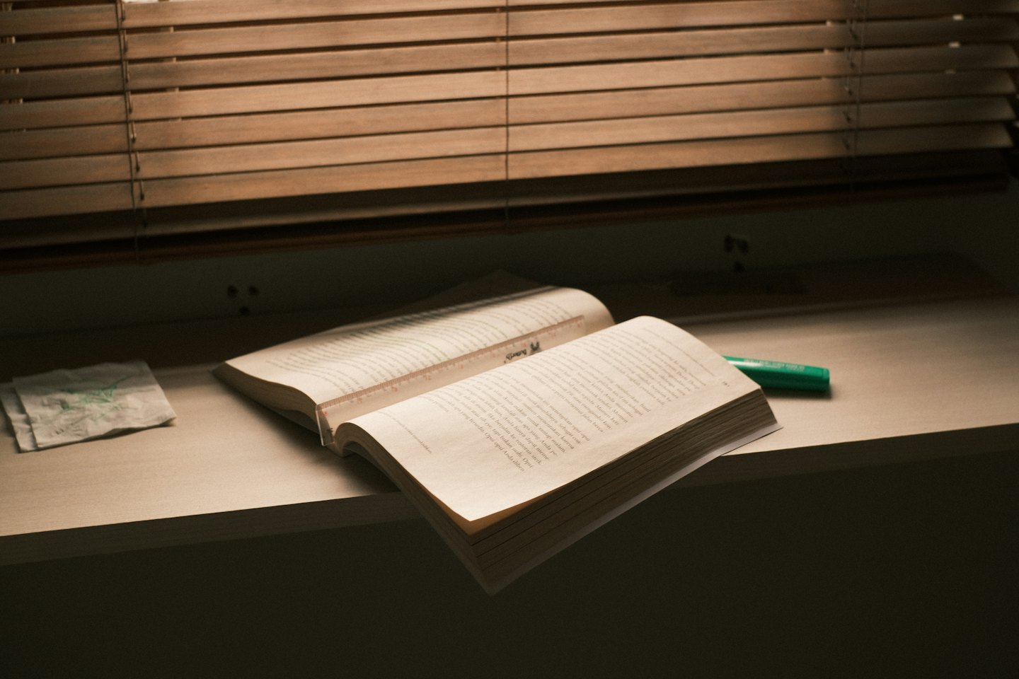 A textbook and stationery sit on a wooden shelf.