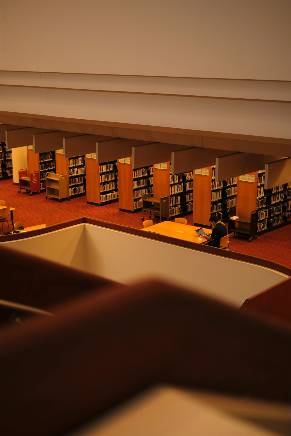 Student studies at a table in a large library with many bookshelves.