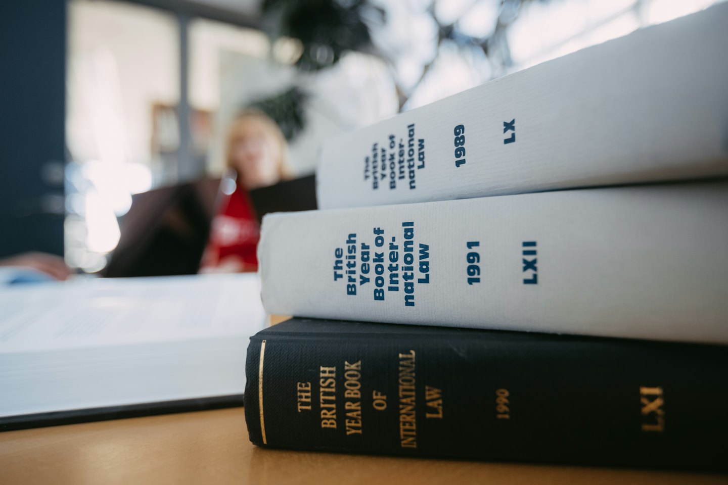Stack of three law books on a wooden desk.